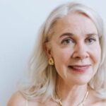 A smiling senior woman with earrings and necklace from a portrait session.